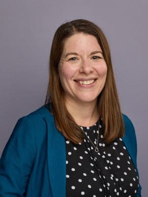 Author photo of Amanda Cave Jackson, New York day trip expert for Busy Moms, wearing black polka dot shirt and turquoise jacket.