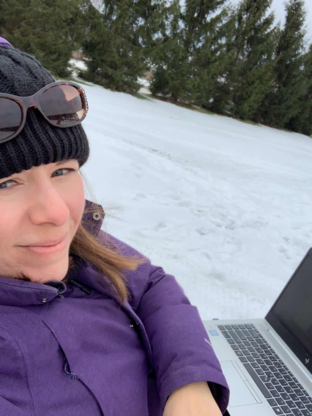 A woman on her laptop working in the snow.