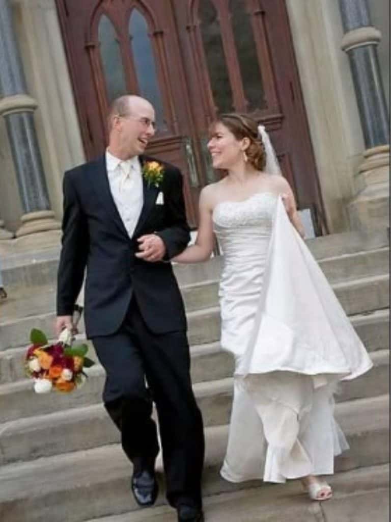 This picture of our wedding shows the start of our family. A woman in a wedding dress and man in a tuxedo after a wedding on church steps smiling.