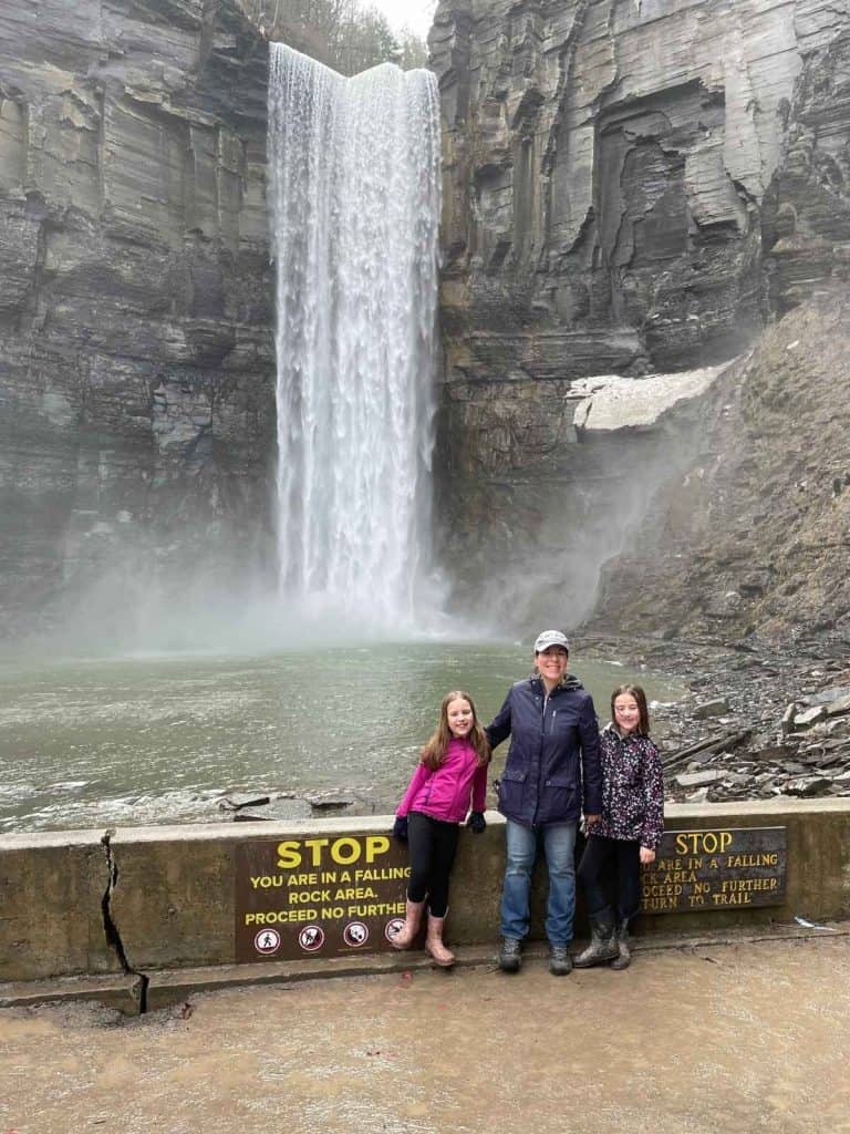 A woman and two girls in coats standing beside waterfalls in Ithaca, NY.